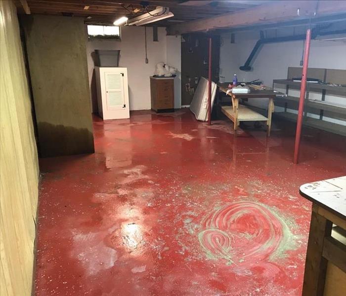 A red basement floor is covered in water. 