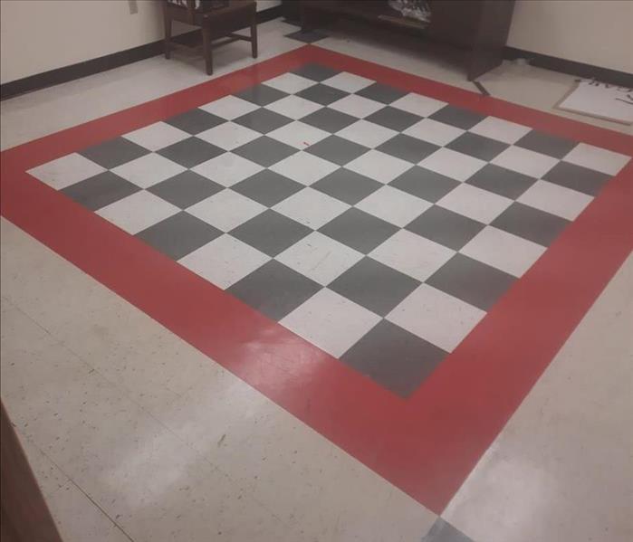 A red, black, and white tiled floor is dirty.