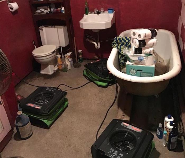 A bathroom has SERVPRO equipment drying the room.