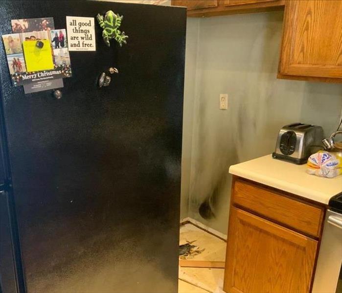 A fridge in a kitchen created fire damage on a wall.