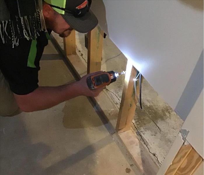image of SERVPRO technician holding a drill with two-foot cuts into residential drywall present