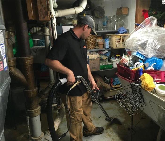 SERVPRO team member is extracting water from a basement floor.