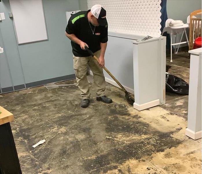 SERVPRO team member is removing vinyl flooring from a commercial building.