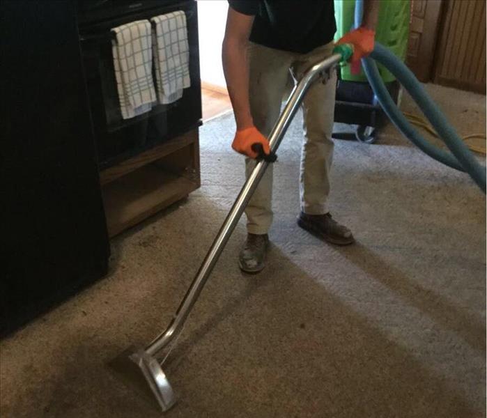 SERVPRO team member is extracting water from a kitchen floor.
