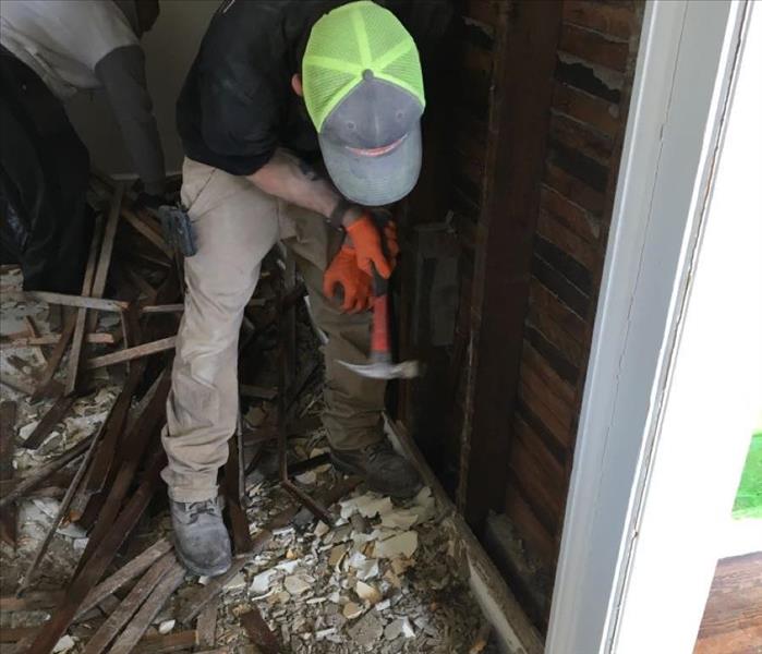 SERVPRO team member is removing plaster from a wall.