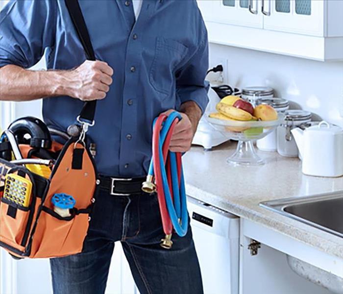 image of person holding belt bag of tools walking through a residential home