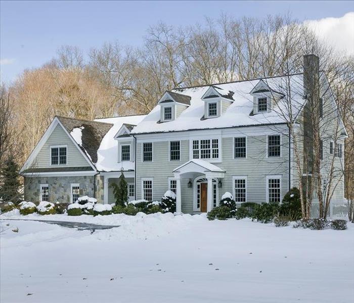 image of home during the winter months with snow on the roof and in the yard
