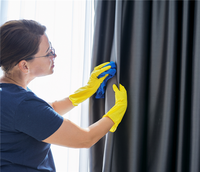 Woman is cleaning curtains.